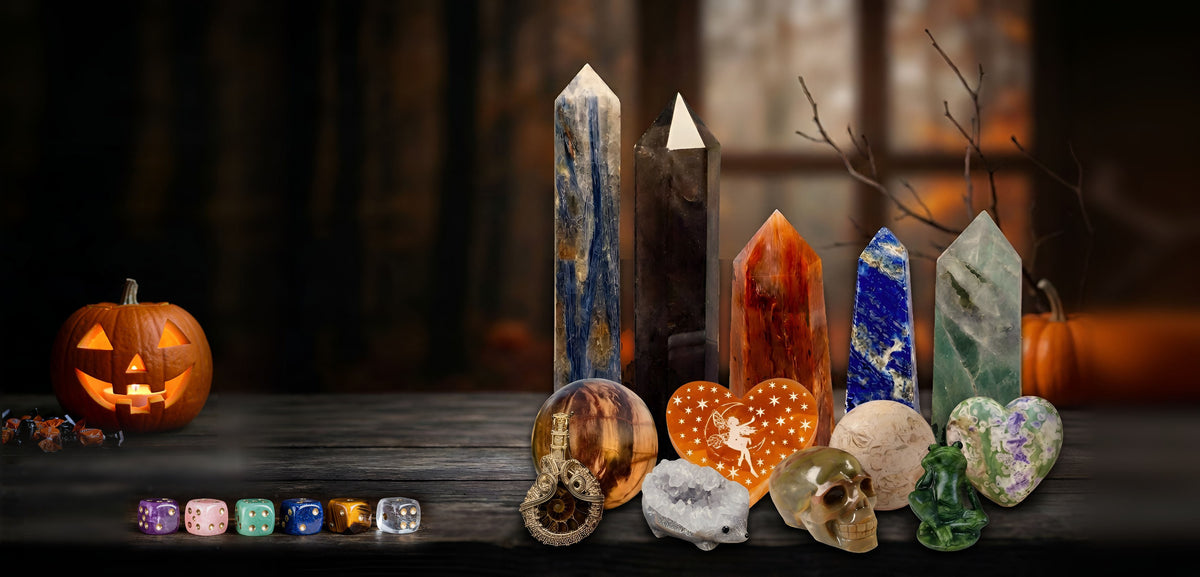 Crystal towers, hearts and novelty carvings with a glowing jack-o'-lantern and crystal dice on a rustic shelf for the October 25% off sale